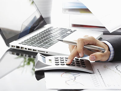 a business man using a calculator in front of a laptop